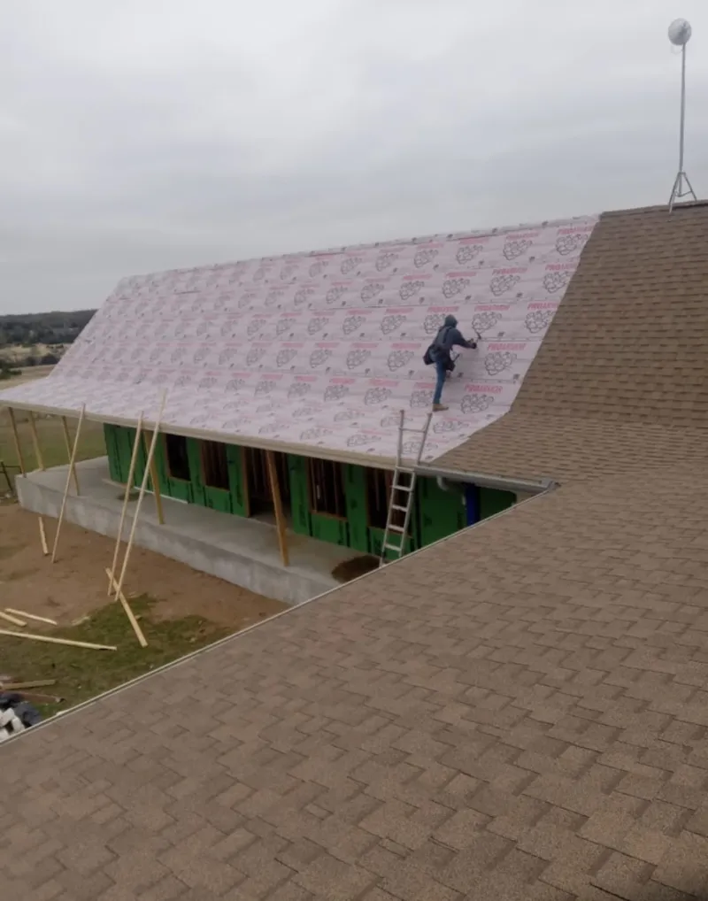 Worker preparing underlayment for a metal roof installation in Seneca